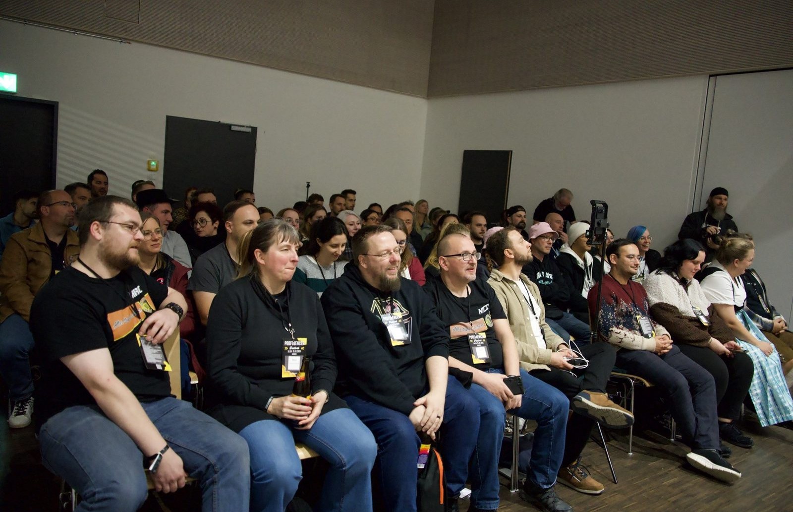 Besucherinnen und Besucher sitzen gespannt in den Stuhlreihen beim Podfluencer Festival in München